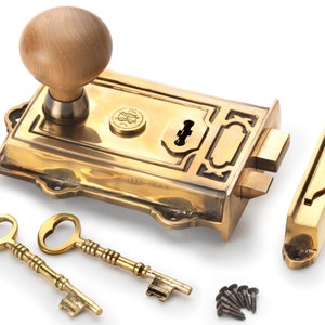 May include: A brass door lock set with a wooden knob, two ornate keys, and a strike plate. The lock features a keyhole and decorative detailing. Includes mounting screws. Ideal for home decor.