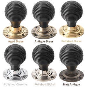 May include: Six door knobs with a black, ribbed spherical handle. The knobs are displayed with various base finishes: Aged Brass, Antique Brass, Polished Brass, Polished Chrome, Polished Nickel, and Matt Antique.