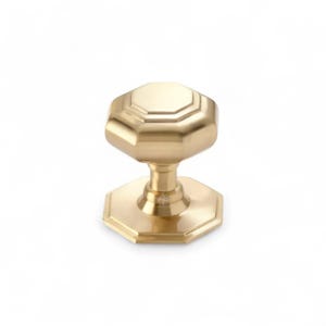 May include: A gold-coloured octagonal cabinet knob with a matching base. The knob has a geometric design and a polished finish. The hardware is likely for furniture or cabinetry.