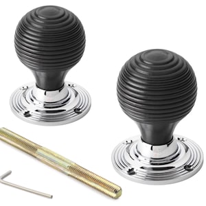 May include: Two black, ribbed door knobs with a polished chrome base. The knobs have a spherical shape and are accompanied by a threaded rod and an Allen key. The hardware is designed for doors and cabinets.