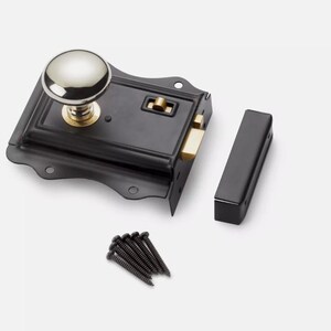 May include: A black door latch with a silver knob and brass detailing. The set includes a strike plate and black screws. This door hardware is designed for use on doors.