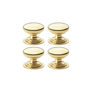 May include: Four gold cabinet knobs with a classic, rounded design. Each knob has a circular top and a decorative base, suitable for drawers or doors. The knobs are made of a shiny, metallic material.