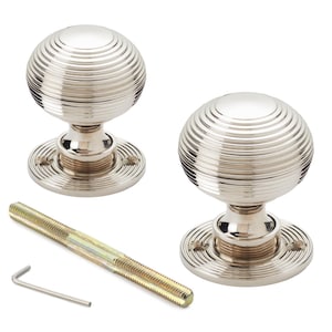 May include: Two polished nickel door knobs with a spherical design featuring concentric ridges. The knobs sit on a circular base with screw holes. A long threaded rod and an Allen key are also included.