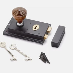 May include: A black door latch with a wooden knob, brass accents, and two keys. Includes a strike plate and screws. The knob is approximately 5 cm in diameter.