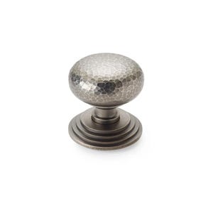 May include: A silver cabinet knob with a hammered texture on the spherical handle. The knob sits on a tiered base. This hardware is ideal for adding a touch of sophistication to furniture. The knob's dimensions are in centimetres.