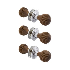 May include: Three wooden door knobs with a ribbed, spherical design. The knobs are a warm brown colour and are attached to a shiny, silver-coloured metal base. The door hardware is set against a plain white background.