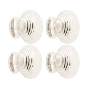 May include: Four silver cabinet knobs with a ribbed, oval design. Each knob has a smooth, rounded base and a polished finish. These decorative knobs are suitable for drawers and cabinets.