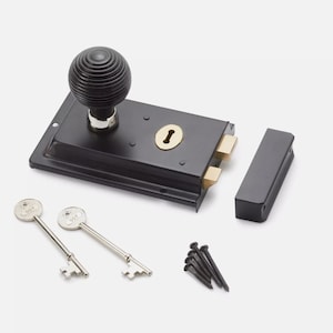 May include: Black door latch with a decorative, ribbed knob, a keyhole, and two keys. The latch has brass-coloured components and comes with a matching strike plate and screws. A classic hardware item.