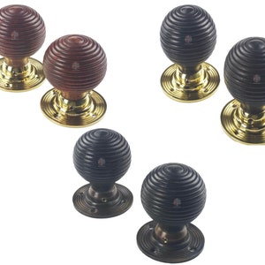 May include: A selection of wooden door knobs with a grooved, spherical design. The knobs are available in dark brown, black, and reddish-brown finishes. Each knob is mounted on a brass or bronze-coloured circular base.