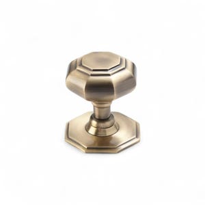 May include: A bronze-toned octagonal door knob with a matching base. The knob features a classic, geometric design, likely made of metal. This hardware is suitable for interior doors and adds a touch of vintage style.