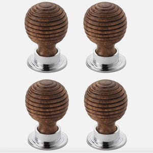 May include: Four wooden cabinet knobs with a spherical design and a grooved texture. The knobs are a warm brown colour and are mounted on a silver-coloured base. The knobs are likely for furniture or cabinetry.