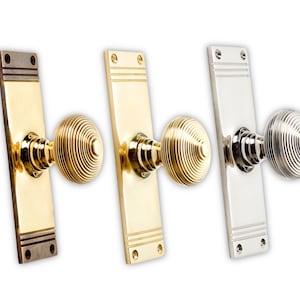 May include: Three door knobs with rectangular backplates. The knobs are round with a spiral design. The backplates and knobs are in three different finishes: bronze, brass, and polished nickel. The door knobs are for interior doors.