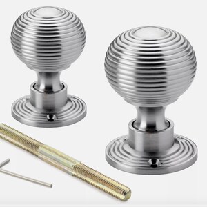 May include: Two brushed nickel door knobs with a spiral design, a threaded rod, and an Allen key. The knobs have a round shape and are mounted on a circular base. Hardware for home improvement.