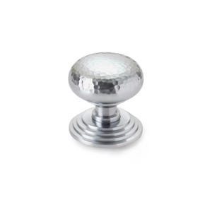 May include: A silver cabinet knob with a hammered texture on the spherical handle. The knob sits on a tiered base with concentric circles. Suitable for drawers, cabinets, and furniture. The knob is approximately 4 cm in diameter.