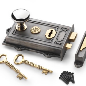 May include: A cast iron door lock set with a polished chrome knob, brass accents, and two ornate keys. The set includes a strike plate and mounting screws, suitable for vintage or antique doors.
