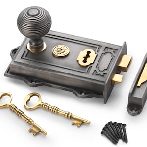 May include: A cast iron door lock set with a decorative knob, brass accents, and two ornate keys. The set includes a strike plate and screws. The lock has a dark grey finish with brass-coloured details.