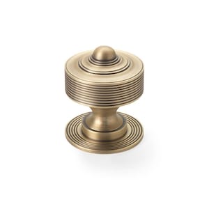 May include: A brass cabinet knob with a circular design. The knob has a small, rounded top, a cylindrical body with horizontal grooves, and a circular base. The hardware is designed for furniture and has a vintage aesthetic.