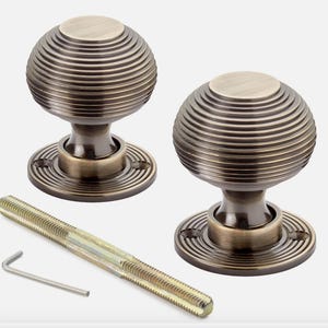 May include: Two antique bronze door knobs with a spiral design, a threaded rod, and an Allen key. The knobs have a round base and a spherical top. The hardware is designed for doors and cabinets.