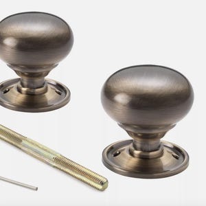 May include: Two bronze-effect door knobs with a spherical design. Each knob is mounted on a circular base. A long threaded rod and an Allen key are also included. Hardware for home improvement.