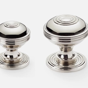 May include: Two polished nickel cabinet knobs. The knobs have a round, ridged design on the top and base, with a smooth, spherical centre. The hardware is designed for furniture and home decor.