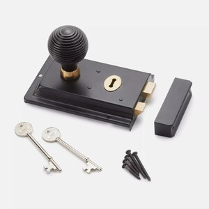 May include: A black door latch with a grooved, round handle and a brass keyhole. Includes two keys, a strike plate, and screws. A traditional design for securing doors.