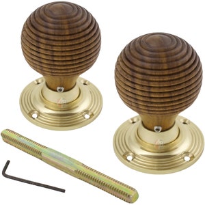 May include: Two wooden door knobs with a grooved, spherical design. The knobs are mounted on brass-coloured circular bases with screw holes. A threaded rod and an Allen key are also included.