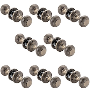May include: Nine antique bronze door knobs with a ribbed, round design. Each knob has a circular backplate with screw holes. The knobs are arranged in three rows of three, showcasing a classic hardware style.