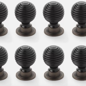 May include: Eight dark bronze cabinet knobs with a ribbed, spherical design. Each knob has a round base and a decorative, textured surface. The knobs are arranged in two rows of four against a white background.
