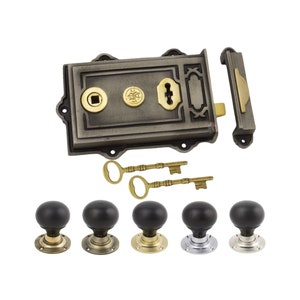 May include: A set of antique-style door hardware. It includes a rectangular, grey lock with brass details, two keys, and five round doorknobs in different finishes. The lock has a decorative design.