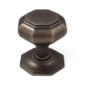 May include: A bronze-coloured cabinet knob with an octagonal design. The knob has a textured surface and a decorative pattern. The base and top of the knob are also octagonal. This hardware is suitable for cabinets and drawers.