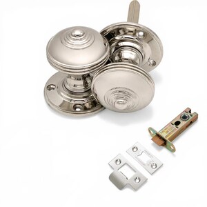 May include: Polished nickel door hardware set. The set includes two round doorknobs with a ridged design, a latch, and two strike plates. The hardware is new and ready for installation.