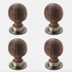 May include: Four wooden cabinet knobs with a spherical design. The knobs are a dark brown colour with a grooved texture, mounted on a brushed metal base. The hardware is suitable for drawers, cabinets, or furniture.