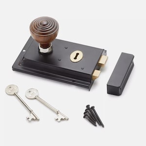 May include: A black door lock set with a wooden knob, brass accents, and two keys. The set includes a strike plate and screws. The knob is a dark brown colour. The keys are silver.