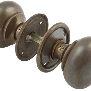Peut inclure: Ensemble de poign&eacute;es de porte en bronze antique, comprenant deux boutons ovales et des plaques arri&egrave;re circulaires. La quincaillerie pr&eacute;sente un design classique avec une finition patin&eacute;e, adapt&eacute;e aux portes int&eacute;rieures. L'ensemble comprend tous les composants n&eacute;cessaires.