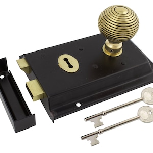 May include: Black door latch with a brass keyhole and a decorative brass knob. Includes two silver keys and a black strike plate. The latch is rectangular and has a classic design.