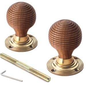 May include: Two wooden door knobs with a grooved, spherical design. The knobs are mounted on brass-coloured circular bases. A threaded rod and an Allen key are also included, suggesting a hardware product.