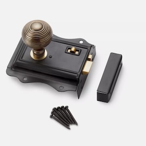 May include: A black door latch with a brass knob and accents. The latch has a decorative shape and includes a matching strike plate and a small pile of black screws. The knob has a ridged design.