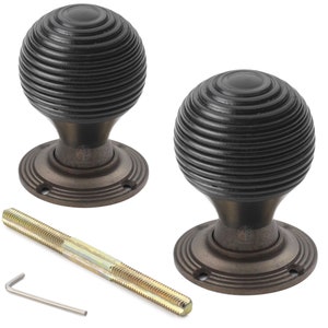 May include: Two antique-style door knobs in a dark bronze finish. Each knob has a spherical shape with a grooved texture. A threaded rod and an Allen key are included. Suitable for interior doors.