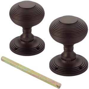 May include: Two bronze door knobs with a ribbed, spherical design. Each knob sits on a circular base with three screw holes. A metal tool rests diagonally across the bottom. Hardware.