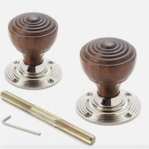 May include: Two wooden door knobs with a layered design, mounted on a silver-coloured base. A threaded rod and an Allen key are included. The knobs have a classic, traditional style.