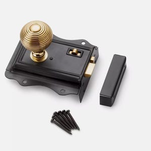 May include: A black door latch with a gold-coloured, spherical doorknob. The latch has a rectangular shape with decorative edges and includes a separate black strike plate and a set of black screws. The doorknob is approximately 5 cm in diameter.