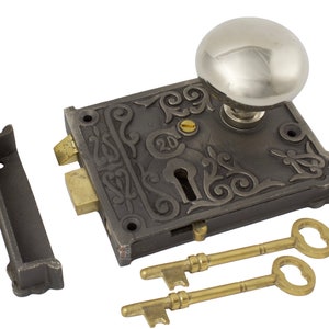 May include: An antique door lock set featuring a silver knob, an ornate dark metal plate, and two brass keys. The set includes a strike plate and is designed for a vintage or classic aesthetic.