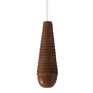 May include: A brown wooden light pull with a ridged design, suspended by a white cord. The pull has a rounded base and a cylindrical shape with horizontal grooves, creating a textured appearance. The pull is approximately 15 cm in length.