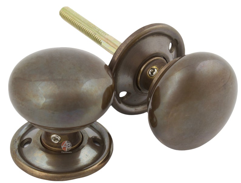 Peut inclure: Deux poign&eacute;es de porte de couleur bronze, de forme arrondie classique. Chaque bouton a une surface lisse et polie et est mont&eacute; sur une plaque arri&egrave;re circulaire. L'ensemble comprend une tige filet&eacute;e pour l'installation. Convient aux portes int&eacute;rieures.