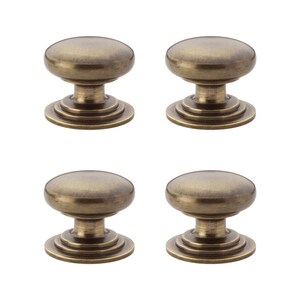 May include: Four antique brass cabinet knobs. Each knob features a rounded top, a short stem, and a tiered base. The knobs are a warm, metallic colour, and are arranged in a square formation against a white background.