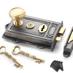 May include: A cast iron door lock set with a brass knob, keyhole cover, and strike plate. Includes two ornate brass keys and black screws. The lock has a dark grey finish with brass accents, suitable for a vintage or antique aesthetic.