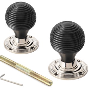 May include: A pair of black, ridged door knobs with polished silver bases. The spherical knobs are shown with a long screw and an Allen key. The door hardware is designed for interior use.
