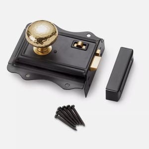 May include: A black door latch set with a hammered gold-coloured knob. The set includes a black strike plate, a black receiver, and a small pile of black screws. The hardware is designed for a door.