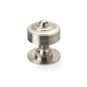 May include: A silver cabinet knob with a ridged, cylindrical body and a rounded top. The knob has a circular base with concentric grooves. The hardware is designed for furniture and cabinetry.