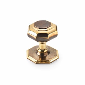 May include: A brass door knob with an octagonal design. The knob features a dark brown central section and a gold-coloured rim. The base of the knob is also octagonal and gold-coloured. Suitable for a door.